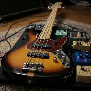 A 5 string electric bass guitar connected to several effects pedals.