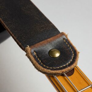 "End of a bass guitar strap securely attached to the guitar's strap button, showing connection point."