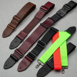  "Variety of bass guitar straps in different colors and materials, including leather and nylon."