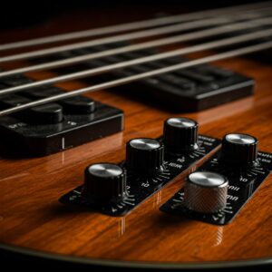 Close view of the electronic control knobs and EQ settings on a 5 string acoustic electric bass guitar.