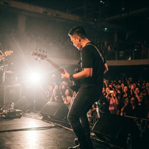Bassist playing a yamaha 5 string bass guitar on stage.