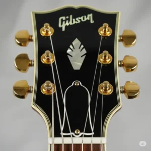 Close-up view of the headstock of an lp custom guitar, highlighting the inlaid logo and gold-plated tuners.