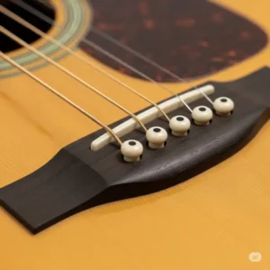 A close look at the bridge and saddle of the $300 wooden guitar, showcasing its solid construction.
