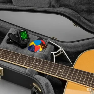 The interior storage compartment of a guitar case, where a tuner, picks, and a capo can be stored alongside the acoustic guitar. acoustic guitar with case